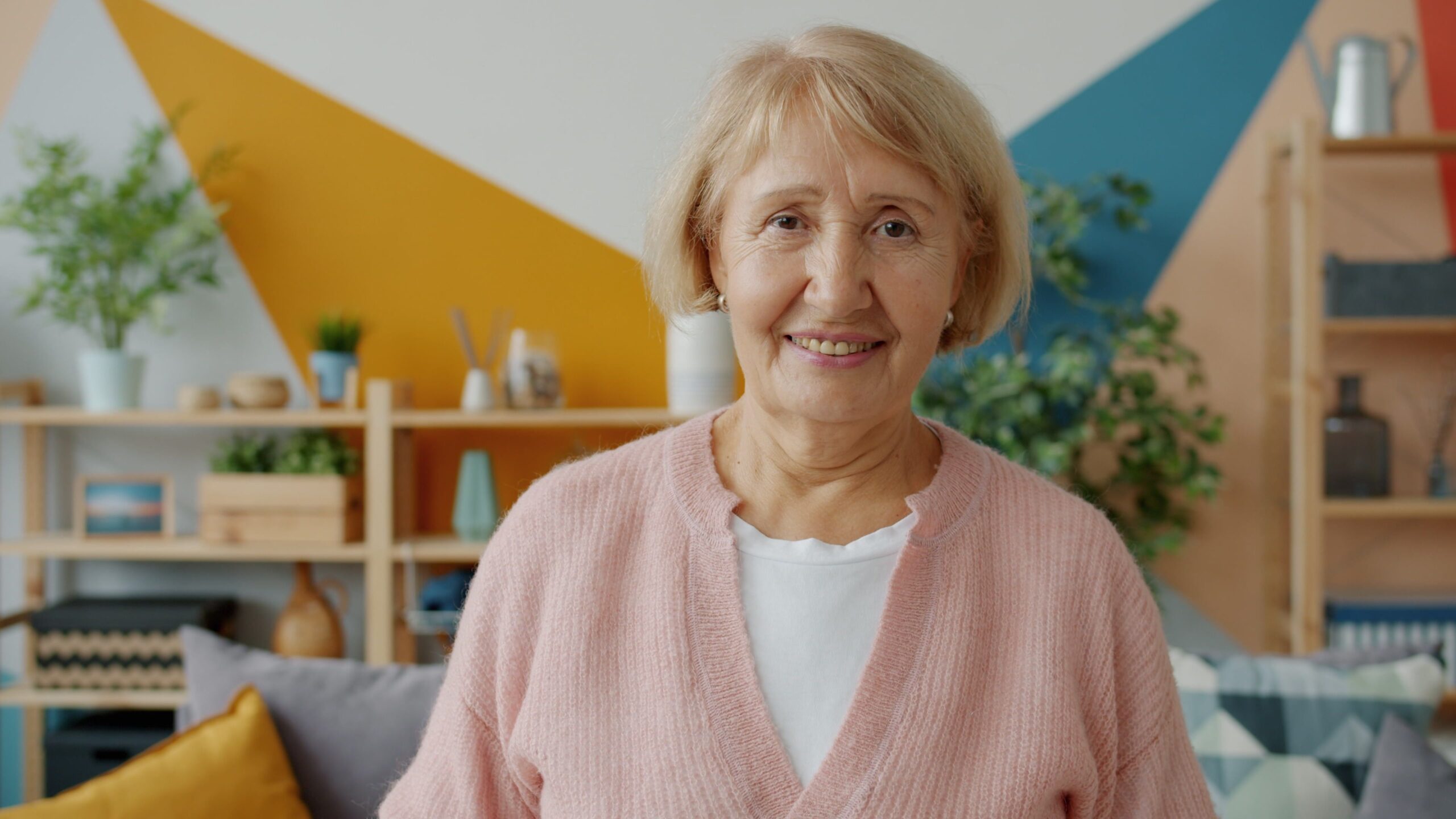 Home Elderly woman smiling in a cozy, colorful living room setting.